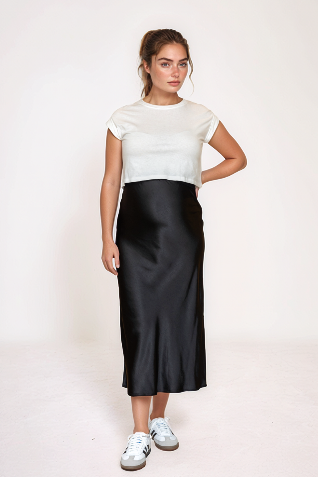 Pregnant woman wearing black satin maternity skirt and cropped white organic cotton t-shirt for the top maternity style trends for 2025 for luxury designer brands in UK Ireland USA doing maternity workwear and maternity occasion wear