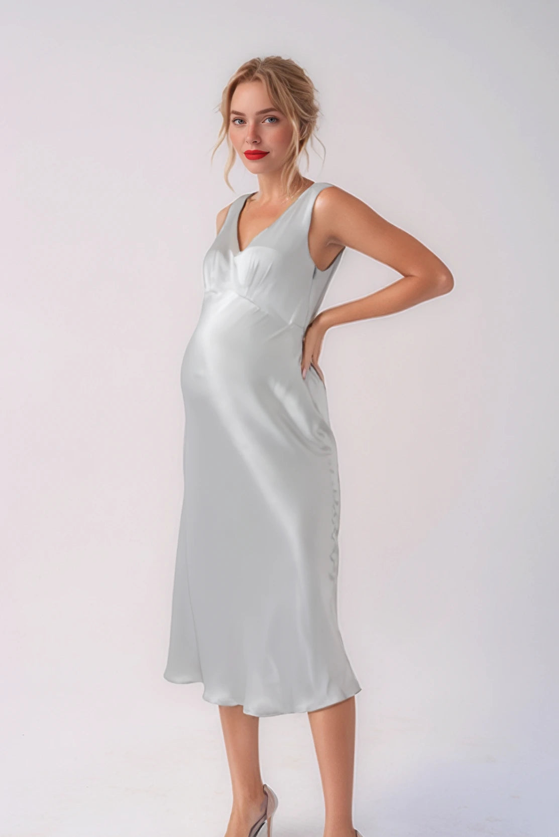 Stylish pregnant woman wearing a stunning silver evening dress at a cocktail party event - CARI is a luxury designer brand for elevated pregnancy style