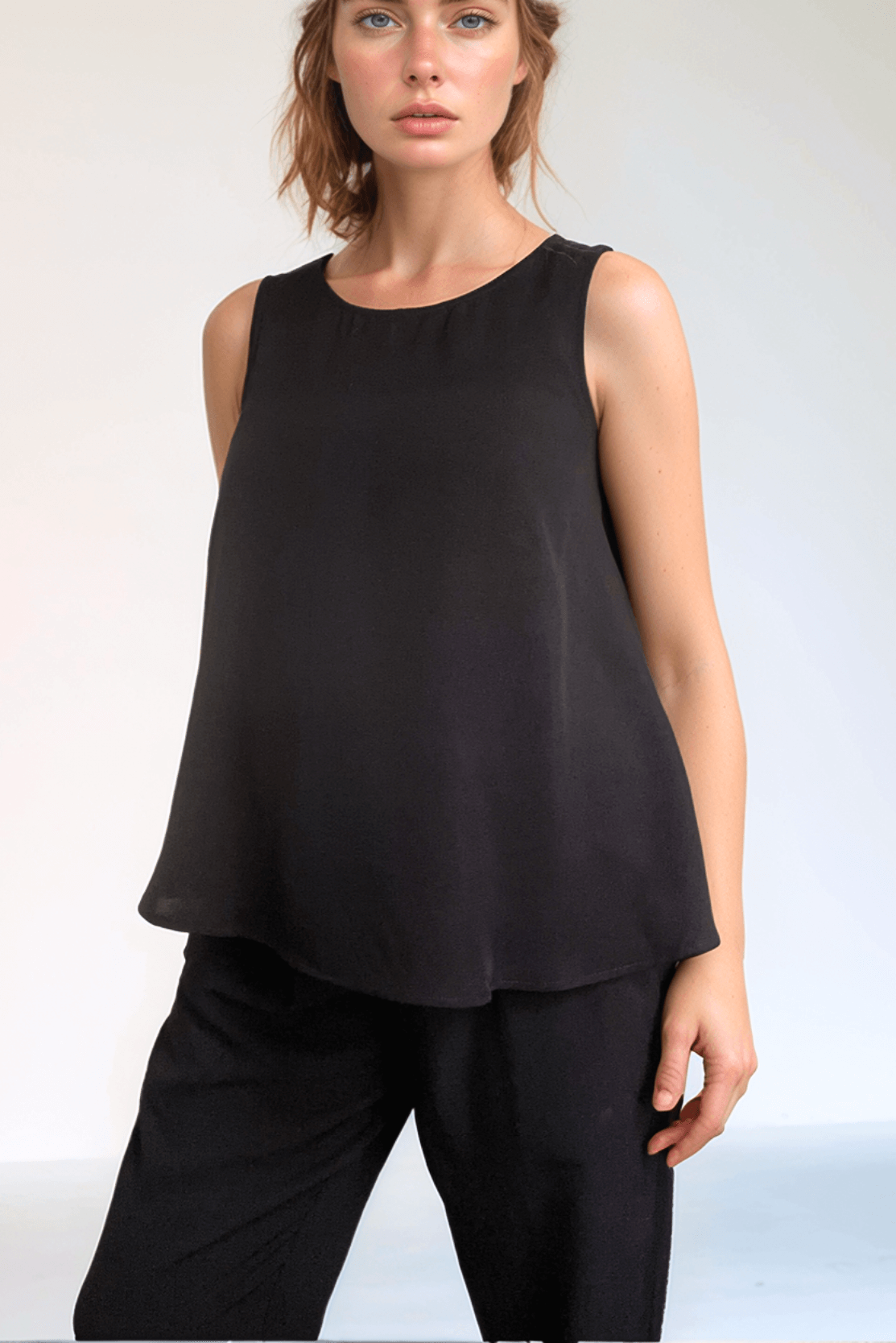 Pregnant woman wearing a minimalist maternity style matching outfit of smart black maternity top and elastic waist trousers